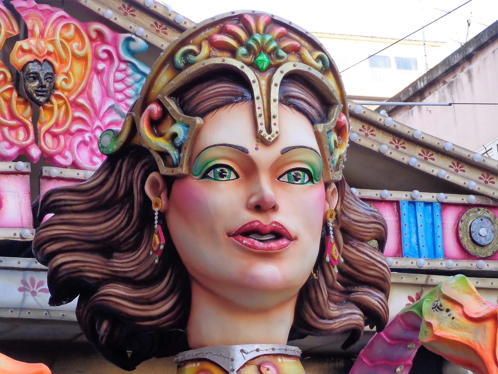 Dettaglio di un carro allegorico in cartapesta del Carnevale di Acireale: un grande volto femminile con elmo decorato e colori accesi