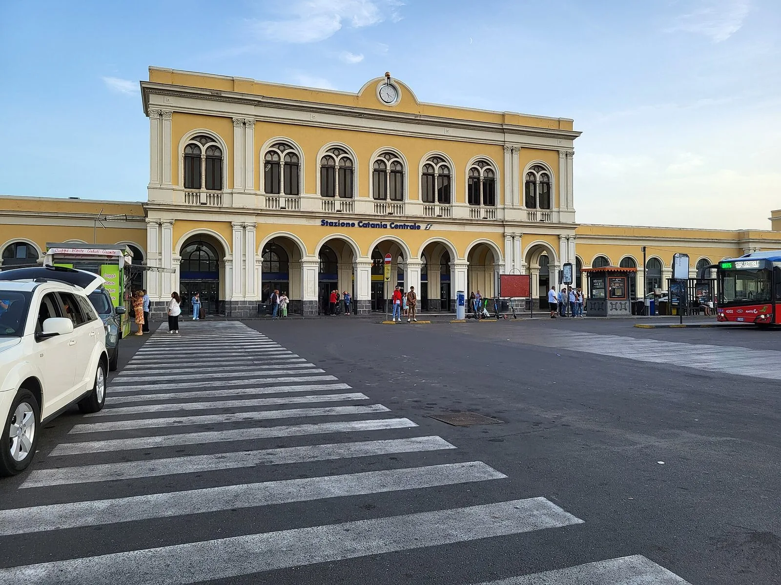 Facciata gialla della stazione Catania Centrale con portici ad arco, vista da piazza Papa Giovanni XXIII