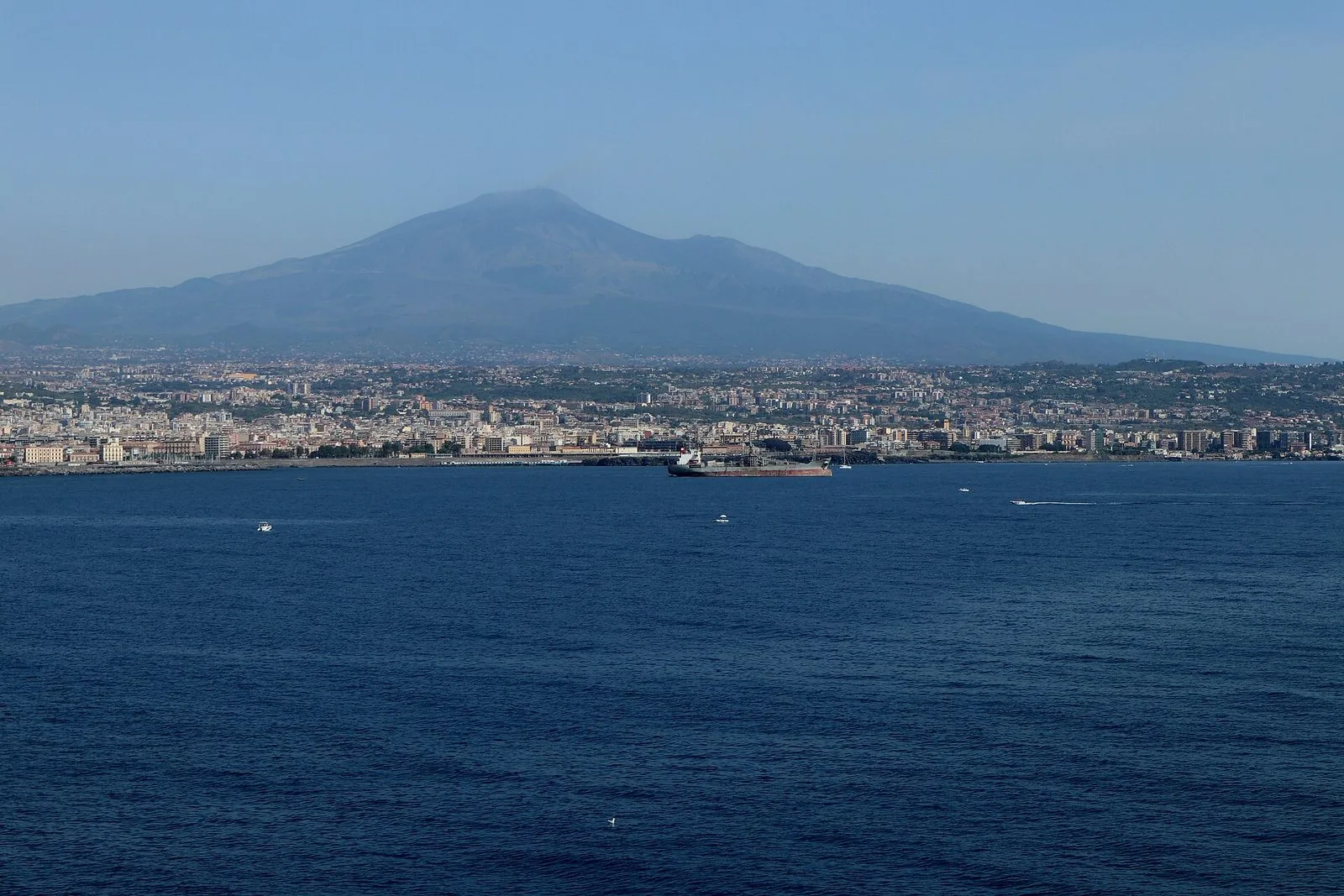 Panorama di Catania vista dal mare, con la città lungo la costa e l'Etna sullo sfondo